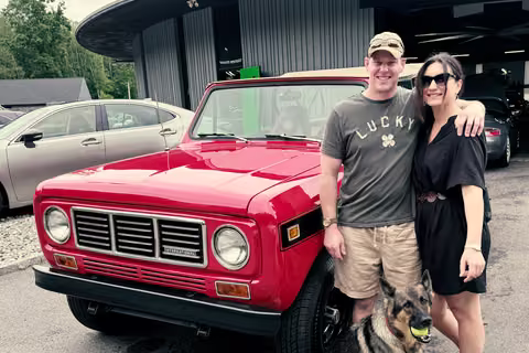 Customers and their dog beside a red 1977 International Harvester Scout II